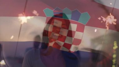 Animation of flag of croatia over happy biracial woman with fireworks. Vacations, patriotism and active lifestyle concept digitally generated video.
