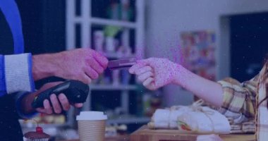 Animation of nft text banner over mid section of woman making a payment by credit card at a cafe. Cryptocurrency and business technology concept