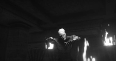 Image of scary zombie mummy walking in dark room with burning torches, in black and white. Halloween fear, horror and suspense concept digitally generated image.