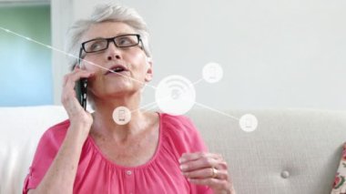 Animation of technology icons connecting with lines over senior caucasian woman talking on cellphone. Digital composite, multiple exposure, telecommunication, retirement. Wireless technology, home.