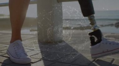 Animation of globe rotating over caucasian woman with prosthetic leg holding coffee and using phone. Digital composite, multiple exposure, drink, lifestyle, global network, technology and disability.