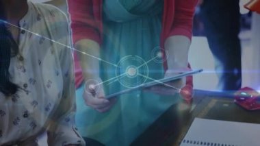 Animation of network of connections over two diverse women discussing over a digital tablet. Global networking and business technology concept