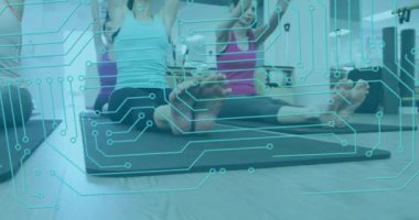Animation of microprocessor connections over group of diverse fit women practicing yoga at the gym. Sports and fitness technology concept