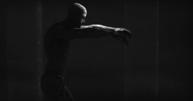 Image of scary zombie mummy walking in dark crypt room, in black and white. Halloween fear, horror and suspense concept digitally generated image.