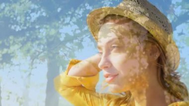 Composite video of caucasian woman wearing a hat smiling against tall trees. Travel and vacation concept
