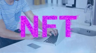 Animation of pink nft text banner over caucasian man using at home. Cryptocurrency and business technology concept