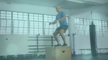 Animation of lens flares over caucasian bald man practicing plyometric exercise on box in gym. Digital composite, multiple exposure, fitness, sport, working out, sport and active lifestyle concept.
