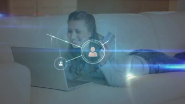 Animation of glowing network of profile icons over caucasian woman using laptop at home. Global networking and business technology concept
