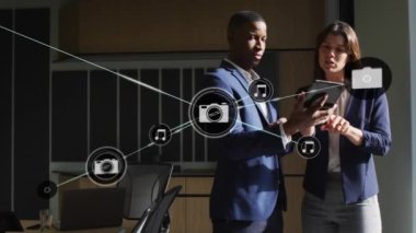Camera and music icons connecting with lines over multiracial coworkers discussing over digital pc. Animation, digital composite, telecommunication, teamwork and technology concept.