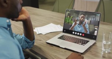 Video of afrcian american man having video call on laptop. Business, communication and working in office with technology concept.