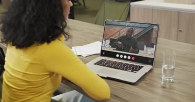 Video of biracial woman having video call on laptop. Business, communication and working in office with technology concept.