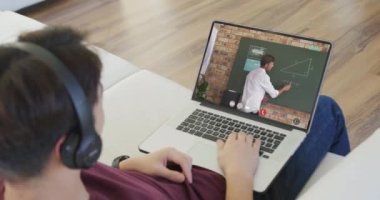 Animation of asian boy in headphones having online lessons on laptop at home. Homeschooling, education and learning with technology concept digitally generated video.