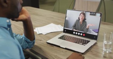 Video of afrcian american man having video call on laptop. Business, communication and working in office with technology concept.