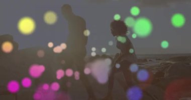 Sahildeki Afrikalı Amerikalı çiftin üzerindeki ışık noktalarının animasyonu. Yaşam tarzı ve boş zaman konsepti dijital olarak oluşturulmuş video.