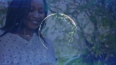Animation of globe with moving lines and numbers over happy young woman texting over cellphone. Digital composite, multiple exposure, communication, global network and technology concept.