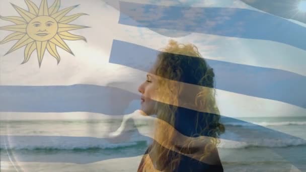 海の波に対してウルグアイフラグを振ってのデジタル組成 旅行休暇愛国心とお祝いのコンセプトデジタル生成ビデオ — ストック動画