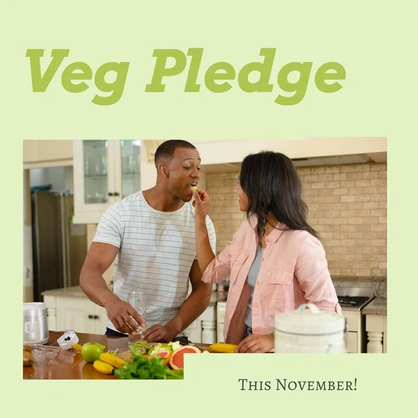 Digital image of biracial girlfriend feeding fruit to boyfriend in kitchen with veg pledge text. Copy space, love, fundraising, challenge, vegetarian, healthy, support and awareness concept.