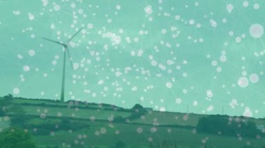Animation of network of connections over spinning windmill on grassland against sky. Global networking and renewable energy technology concept