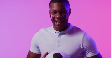 Pembe ışıkta Fransa bayrağı taşıyan mutlu Afro-Amerikan erkek futbol taraftarı portresi. Spor, hareket, eğitim ve aktif yaşam tarzı kavramı.