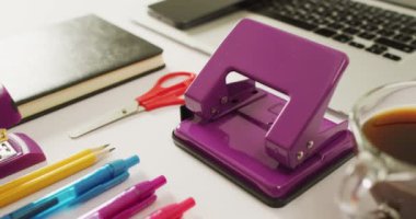 Video of diverse colorful pen, notebook, scissors and punch lying on desk. Business, working in office, equipment and tools concept.