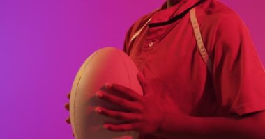 Neon pembe ışıkta rugby topu ile Afrika kökenli Amerikalı bayan rugby oyuncusu. Spor, hareket, eğitim ve aktif yaşam tarzı kavramı.