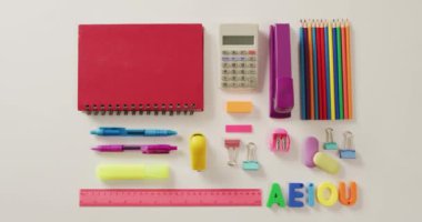Video of composition of school items with notebook and calculator on white background. School equipment, tools, learning and education concept.