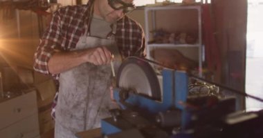 Animation of glowing light over caucasian man working in workshop. labor day, work, workers, tradition and celebration concept digitally generated video.