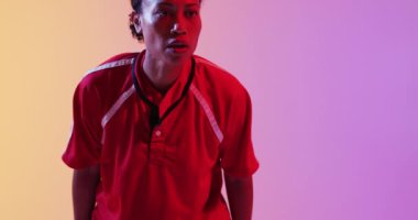 Neon pembe ışıkta rugby topu yakalayan Afrikalı Amerikalı bayan rugby oyuncusu. Spor, hareket, eğitim ve aktif yaşam tarzı kavramı.