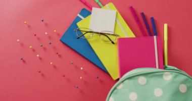 Video of composition of school items, glasses and case on pink surface. School equipment, tools, learning and education concept.