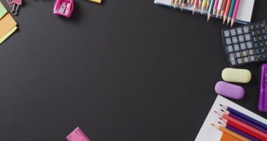 Video of school supplies and notebooks, paper clips, pens over black background. Education, learning and creativity