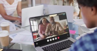 African american woman using laptop for video call, with diverse business colleagues on screen. Business communication technology and remote home working, digital composite video.