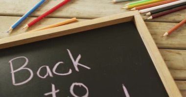Video of tablet with back to school and school items on wooden background. School equipment, tools, learning and education concept.