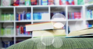 Animation of glowing spots of light over books in library. international literacy day and reading concept digitally generated video.
