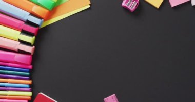 Video of school supplies and notebooks, paper clips, pens over black background. Education, learning and creativity