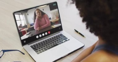African american woman using laptop for video call, with business colleague on screen. Business communication technology and remote home working, digital composite video.