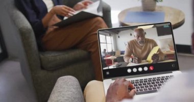 African american man using laptop for video call, with business colleague on screen. Business communication technology and remote home working, digital composite video.