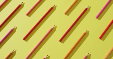 Video of multi-colored crayons in a row on a yellow background. Education, learning and creativity