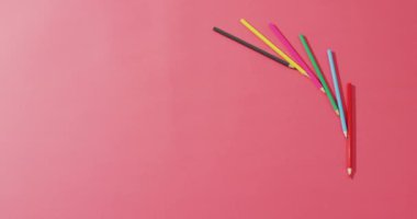 Video of composition with colorful crayons on pink surface with copy space. School equipment, tools, learning and creativity concept.
