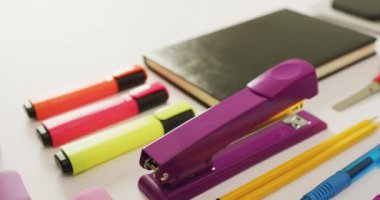 Video of diverse colorful pen, notebook, scissors and punch lying on desk. Business, working in office, equipment and tools concept.