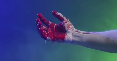 Video of hand covered with blood moving over smoke on black background. Halloween, autumn, tradition and celebration concept.