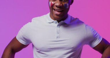 Pembe ışıkta Fransa bayrağı taşıyan mutlu Afro-Amerikan erkek futbol taraftarı portresi. Spor, hareket, eğitim ve aktif yaşam tarzı kavramı.