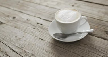 Video of white cup of coffee with milk over wooden background. Coffee, refreshment and beverages.