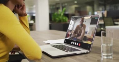 Biracial woman using laptop for video call, with business colleague on screen. Business communication technology and remote home working, digital composite video.