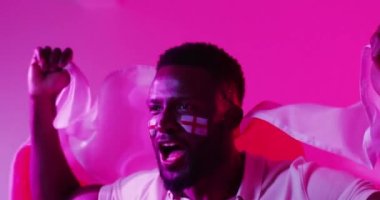 Neon pembe yıldırımlı İngiliz bayrağı taşıyan neşeli Afro-Amerikan erkek spor hayranı videosu. Spor, hareket, eğitim ve aktif yaşam tarzı kavramı.