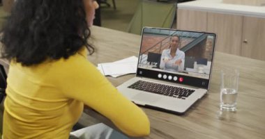 Biracial woman using laptop for video call, with business colleague on screen. Business communication technology and remote home working, digital composite video.