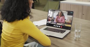 Biracial woman using laptop for video call, with business colleague on screen. Business communication technology and remote home working, digital composite video.