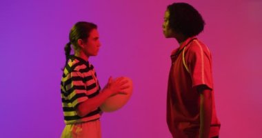 Neon pembe ışıkta rugby topu taşıyan çeşitli bayan rugby oyuncuları. Spor, hareket, eğitim ve aktif yaşam tarzı kavramı.