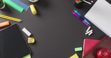 Video of school supplies and notebooks, paper clips, pens over black background. Education, learning and creativity