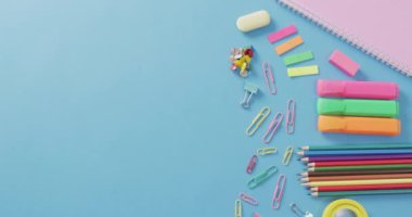 Video of various office supplies, pens, paper clips, pins on blue background. Education, learning and creativity.