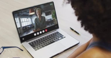African american woman using laptop for video call, with business colleague on screen. Business communication technology and remote home working, digital composite video.